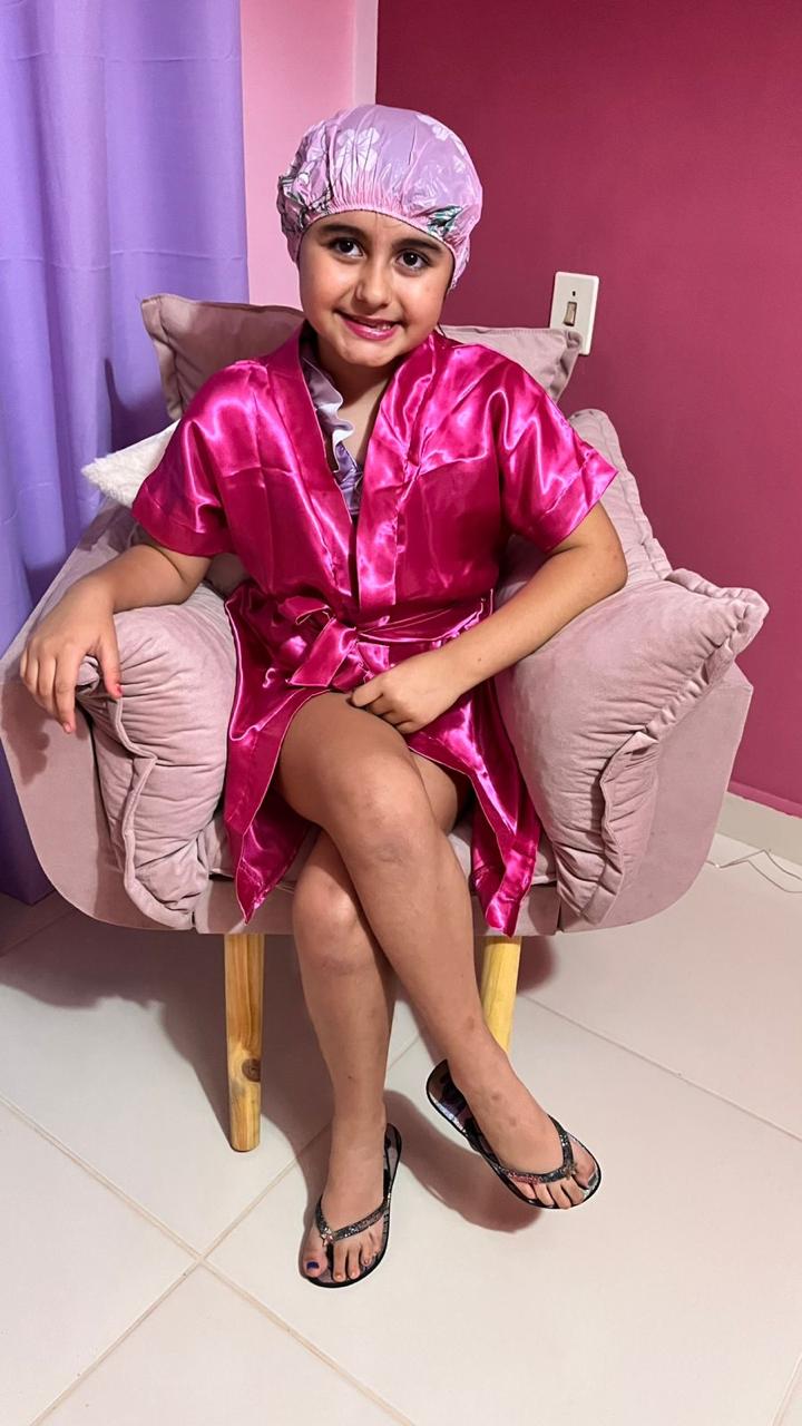 Princesa de roupão e touca na poltrona rosa